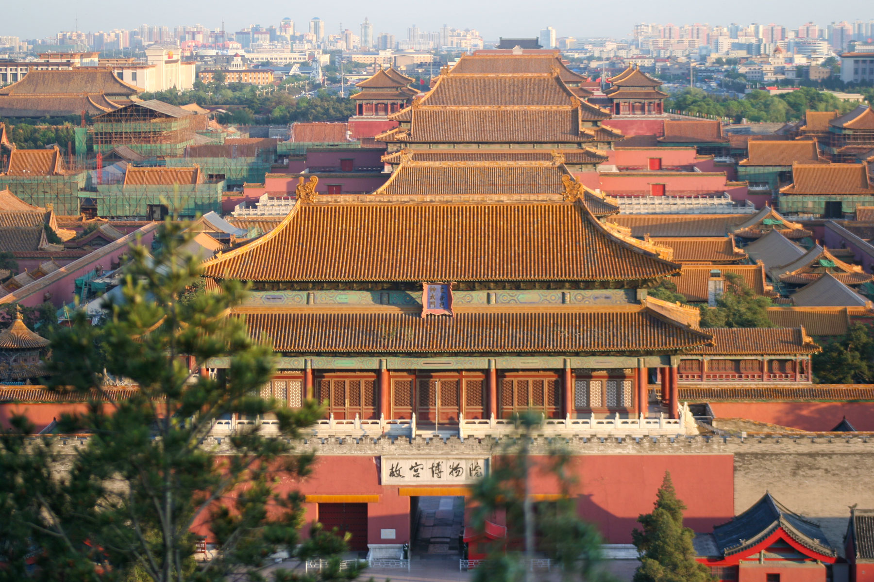 A view along a detailed red and gold corridor with open doors in the Forbidden City.